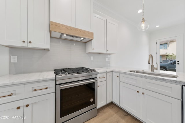 kitchen with backsplash, gas range, white cabinetry, and sink