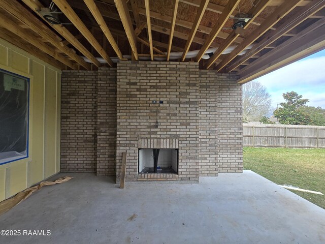 view of patio with an outdoor brick fireplace and fence