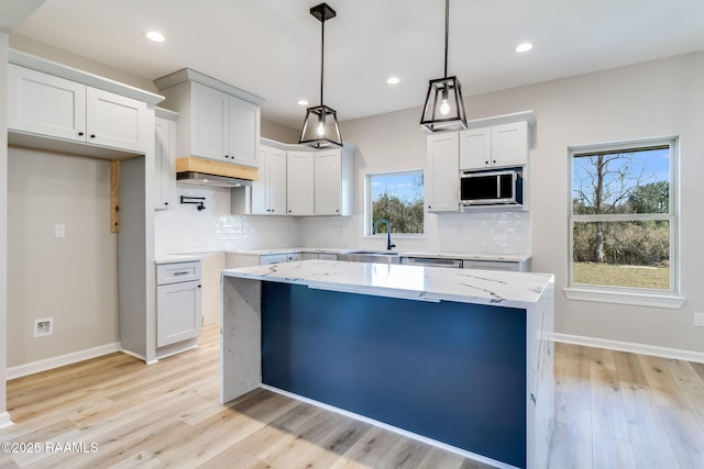 kitchen featuring white cabinetry, sink, a center island, light hardwood / wood-style flooring, and pendant lighting