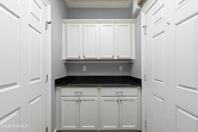 kitchen with white cabinetry, crown molding, and dark stone counters