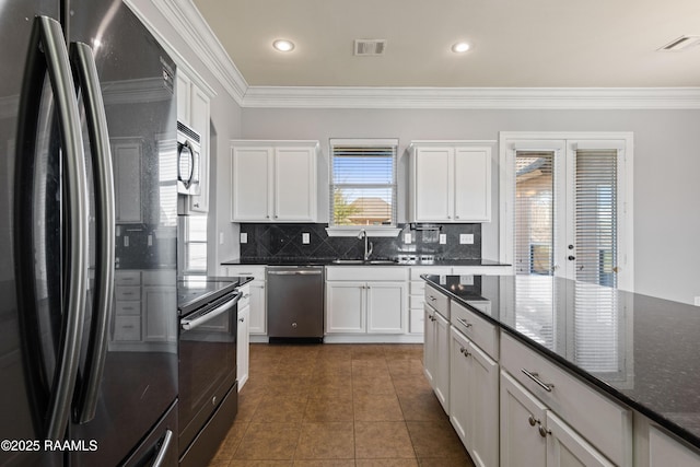 kitchen featuring appliances with stainless steel finishes, backsplash, dark tile patterned floors, dark stone countertops, and white cabinetry