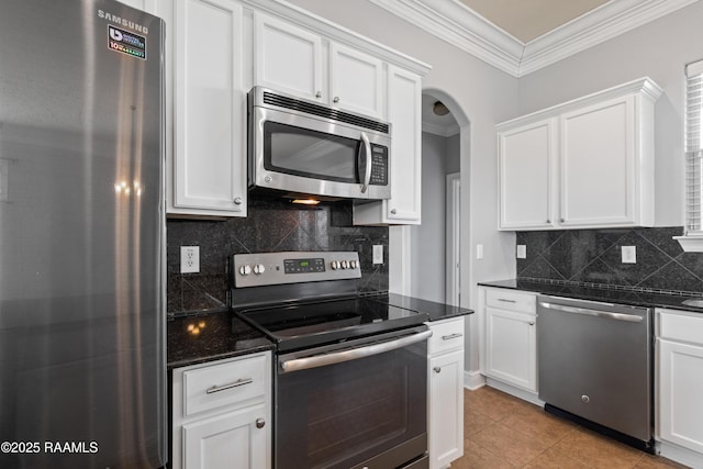 kitchen with backsplash, dark stone counters, white cabinets, light tile patterned floors, and stainless steel appliances