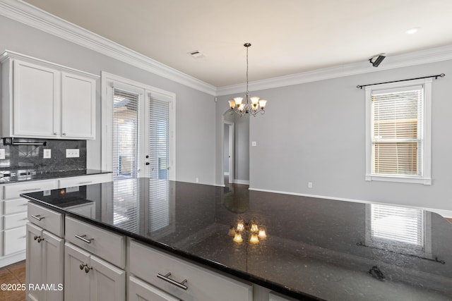 kitchen featuring french doors, a chandelier, dark stone counters, decorative light fixtures, and white cabinets