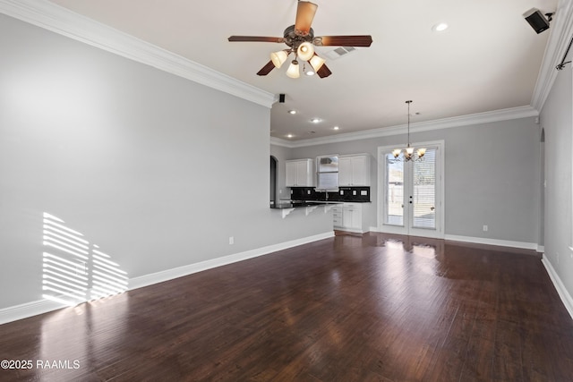 unfurnished living room with french doors, ceiling fan with notable chandelier, dark wood-type flooring, and ornamental molding