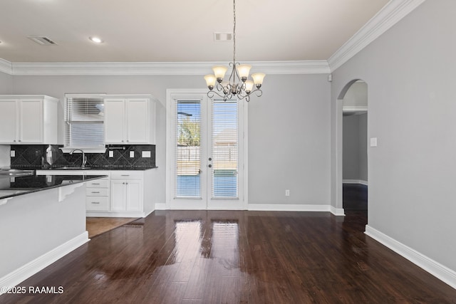 kitchen with decorative backsplash, dark stone counters, crown molding, decorative light fixtures, and white cabinets