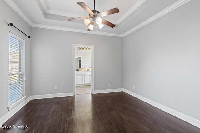 spare room featuring a tray ceiling, ceiling fan, ornamental molding, and dark hardwood / wood-style floors