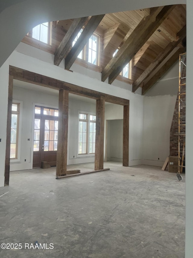 interior space with a healthy amount of sunlight, beam ceiling, and high vaulted ceiling