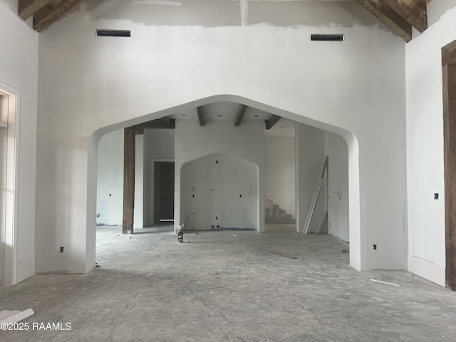 unfurnished living room with high vaulted ceiling and beam ceiling