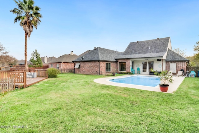 rear view of property with a lawn and a pool side deck