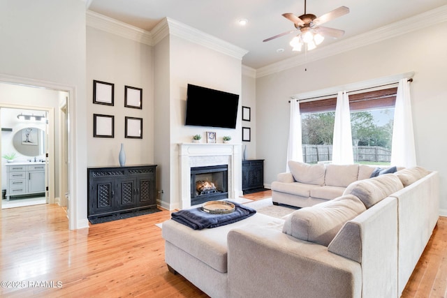 living room featuring ceiling fan, light hardwood / wood-style flooring, sink, and ornamental molding