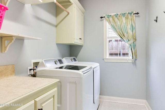 clothes washing area featuring washer and dryer, light tile patterned floors, and cabinets