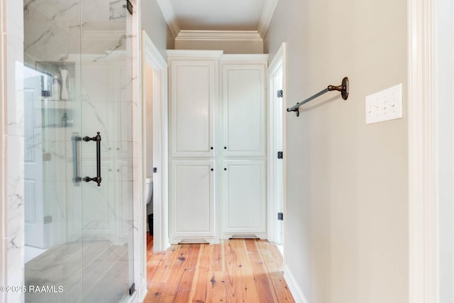 bathroom with hardwood / wood-style floors, toilet, a shower with door, and ornamental molding