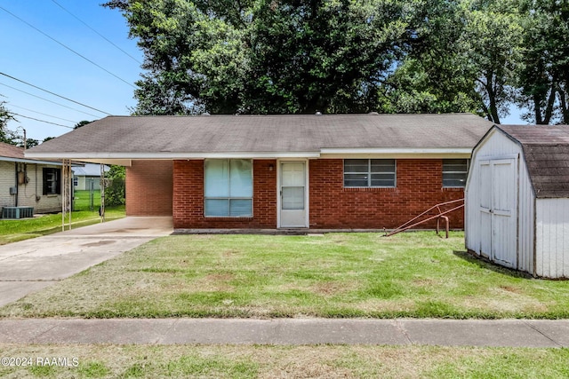 view of front facade featuring a carport, a storage unit, a front yard, and central AC