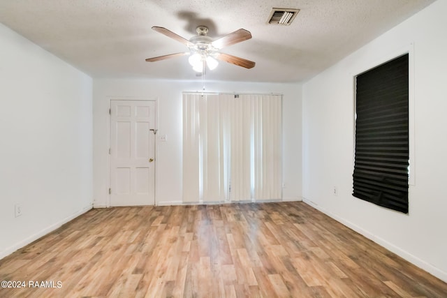 spare room featuring ceiling fan, light wood-type flooring, and a textured ceiling