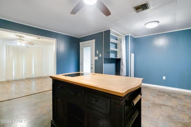 kitchen with crown molding, ceiling fan, a center island, and stovetop