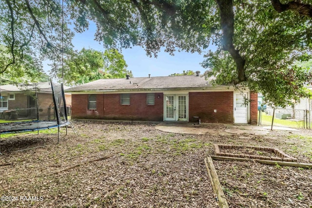 rear view of property featuring french doors, a patio, and a trampoline