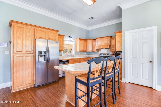 kitchen featuring tile counters, stainless steel refrigerator with ice dispenser, a textured ceiling, dishwashing machine, and a kitchen island