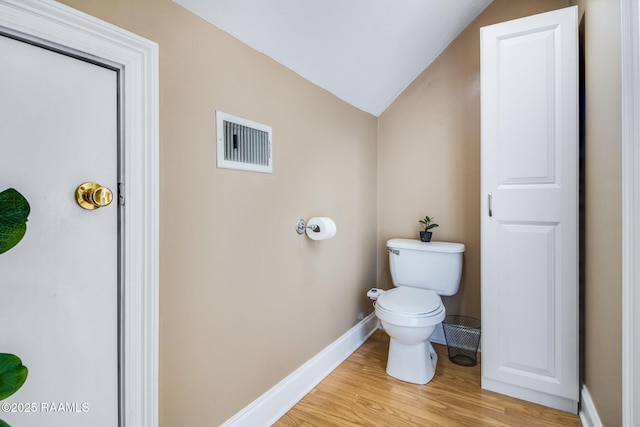 bathroom featuring wood-type flooring, vaulted ceiling, and toilet