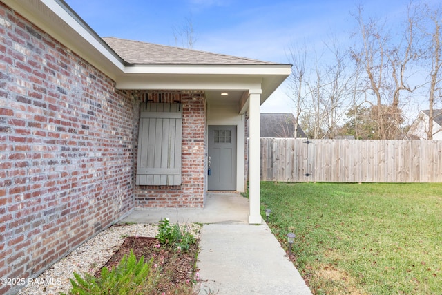 view of exterior entry featuring a lawn