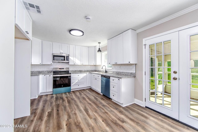 kitchen featuring appliances with stainless steel finishes, tasteful backsplash, a textured ceiling, pendant lighting, and white cabinetry