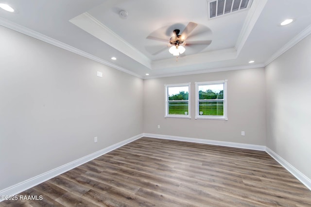 empty room with dark wood-type flooring, a tray ceiling, ceiling fan, and ornamental molding