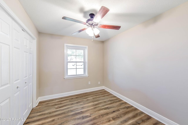 unfurnished bedroom with a textured ceiling, a closet, ceiling fan, and dark wood-type flooring