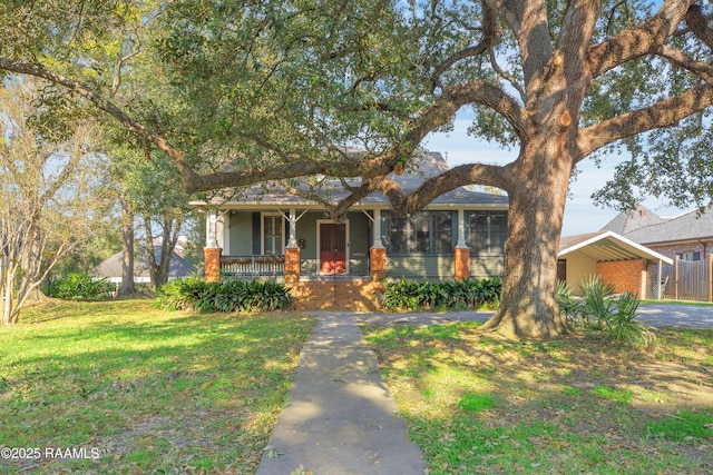 view of property hidden behind natural elements featuring a carport, a porch, and a front yard