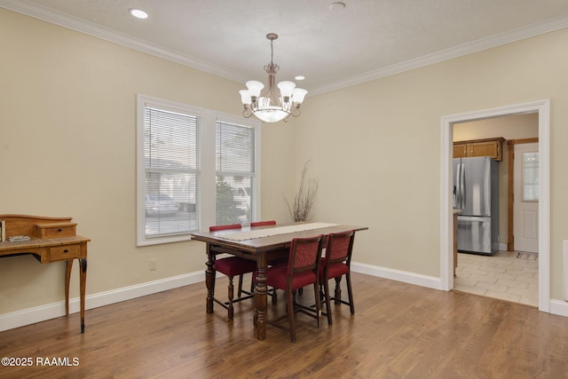 dining space featuring light hardwood / wood-style floors, ornamental molding, and an inviting chandelier