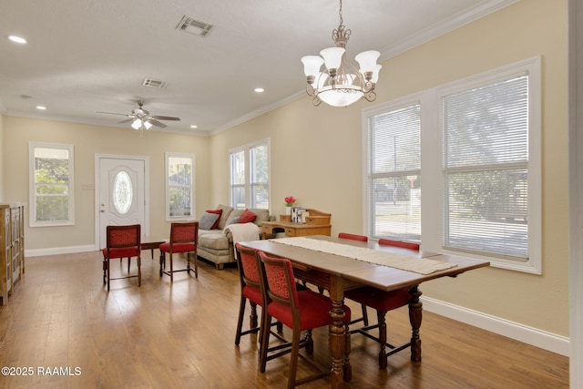 dining room with ceiling fan with notable chandelier, ornamental molding, and hardwood / wood-style floors