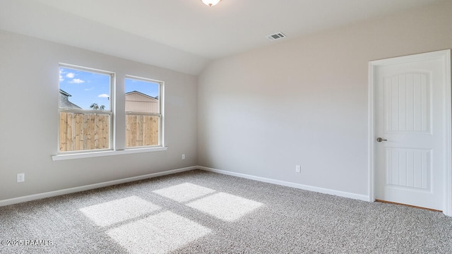 carpeted empty room featuring visible vents, baseboards, and vaulted ceiling