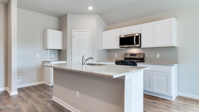 kitchen featuring light stone counters, wood finished floors, a sink, and stainless steel appliances