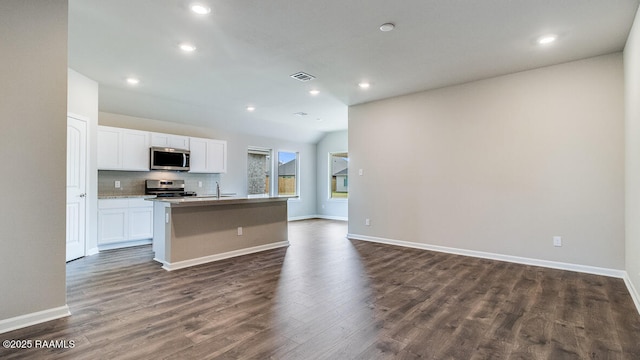 kitchen with open floor plan, dark wood finished floors, an island with sink, and stainless steel appliances