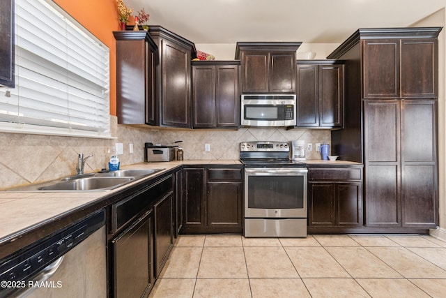 kitchen with appliances with stainless steel finishes, light tile patterned floors, dark brown cabinets, and backsplash