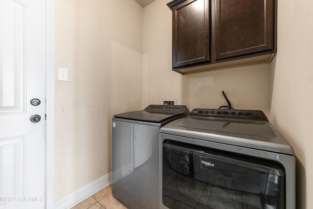 washroom with separate washer and dryer, light tile patterned floors, and cabinets