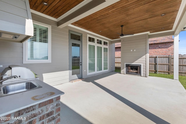 view of patio / terrace featuring ceiling fan, sink, and exterior fireplace