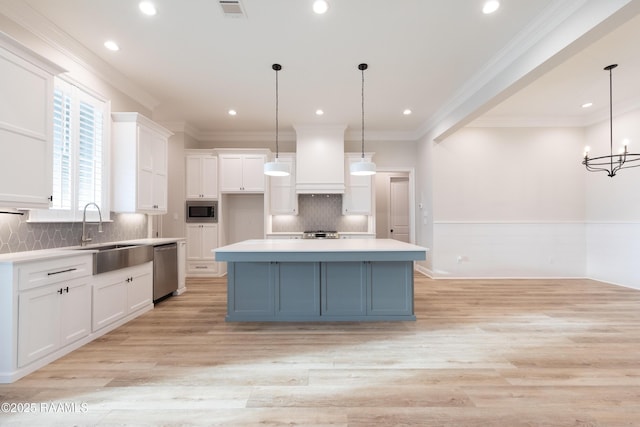 kitchen with appliances with stainless steel finishes, white cabinets, hanging light fixtures, custom exhaust hood, and a spacious island