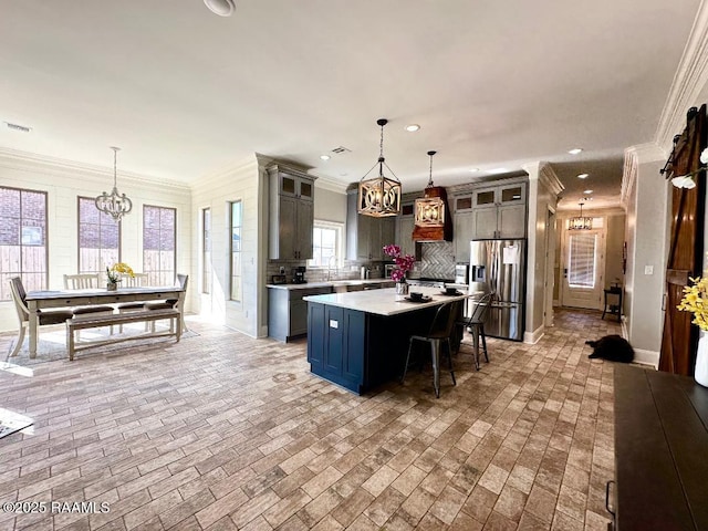 kitchen featuring a breakfast bar area, a chandelier, hanging light fixtures, a center island, and stainless steel fridge with ice dispenser