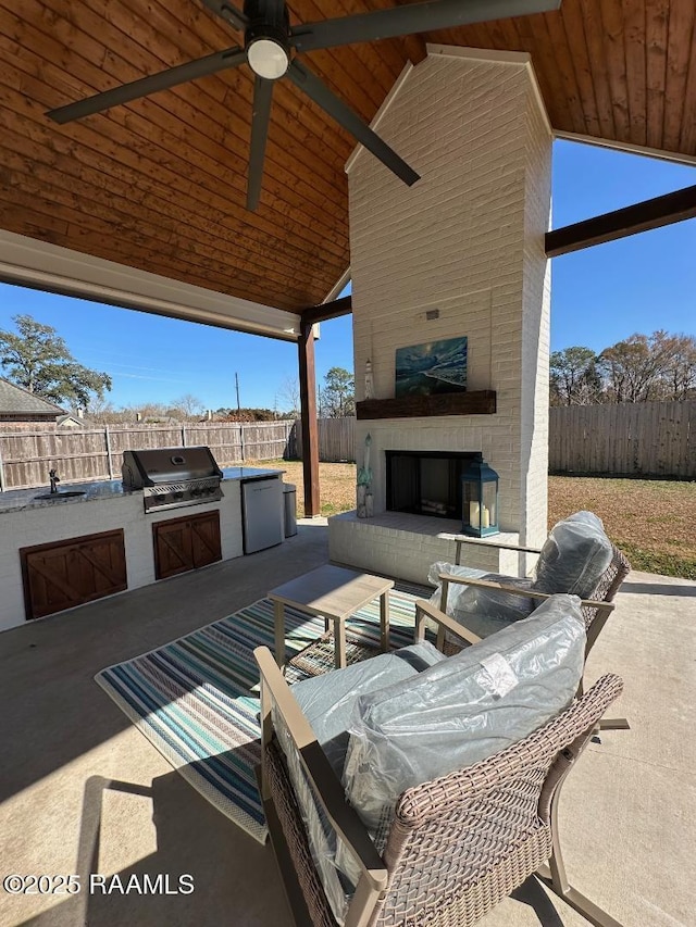 view of patio featuring an outdoor brick fireplace, area for grilling, and ceiling fan