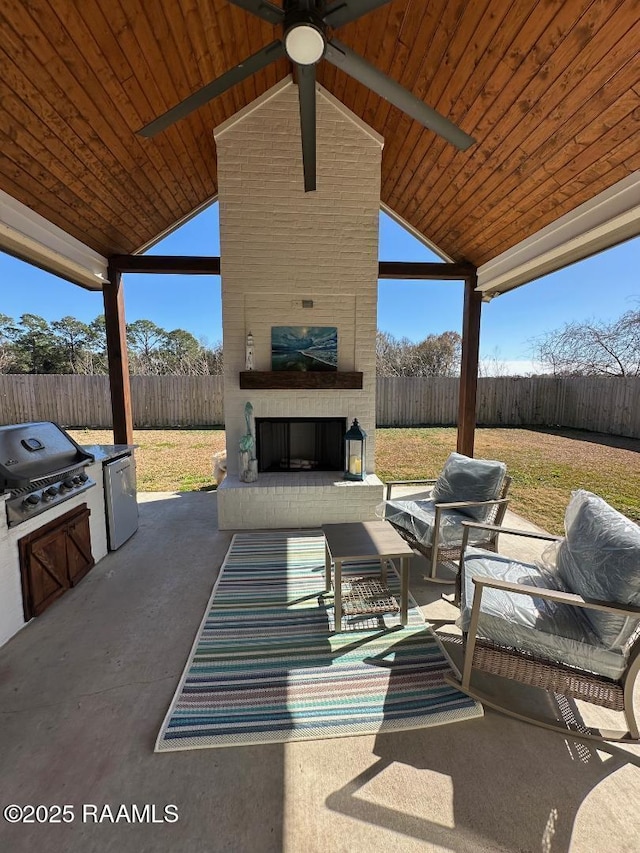 view of patio with an outdoor brick fireplace, exterior kitchen, area for grilling, and ceiling fan