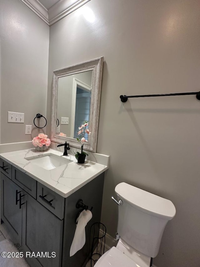 bathroom featuring ornamental molding, vanity, and toilet