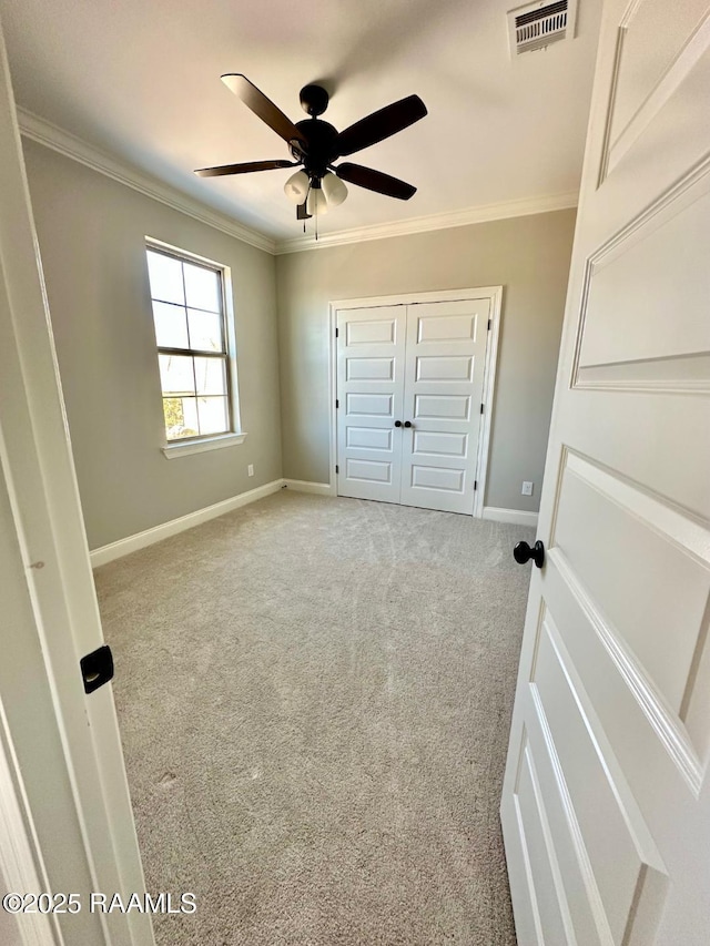 unfurnished bedroom with light carpet, crown molding, a closet, and ceiling fan