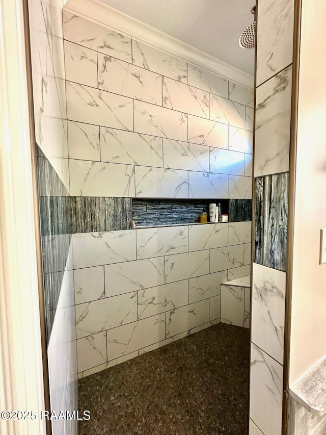 bathroom with a tile shower and crown molding