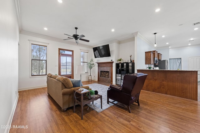 living room with ceiling fan, ornamental molding, and hardwood / wood-style floors