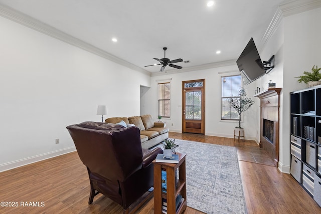 living room with ceiling fan, a fireplace, crown molding, and hardwood / wood-style floors