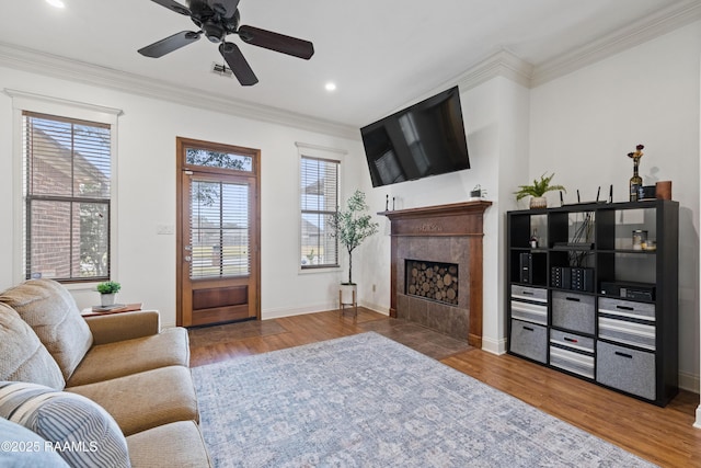 living room featuring ceiling fan, ornamental molding, a fireplace, and hardwood / wood-style floors