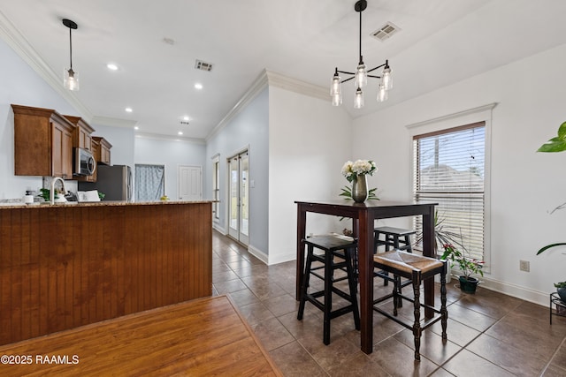 kitchen with hanging light fixtures, dark tile patterned floors, appliances with stainless steel finishes, and light stone counters