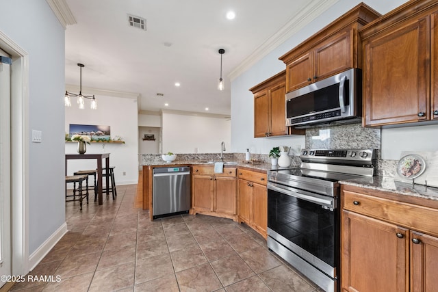 kitchen with appliances with stainless steel finishes, pendant lighting, ornamental molding, and tasteful backsplash