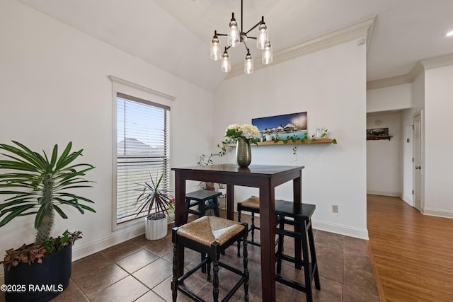 dining space featuring vaulted ceiling, dark tile patterned flooring, ornamental molding, and a notable chandelier