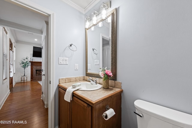 bathroom with hardwood / wood-style floors, toilet, vanity, and ornamental molding