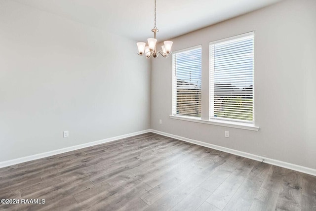 unfurnished room with hardwood / wood-style flooring and a chandelier